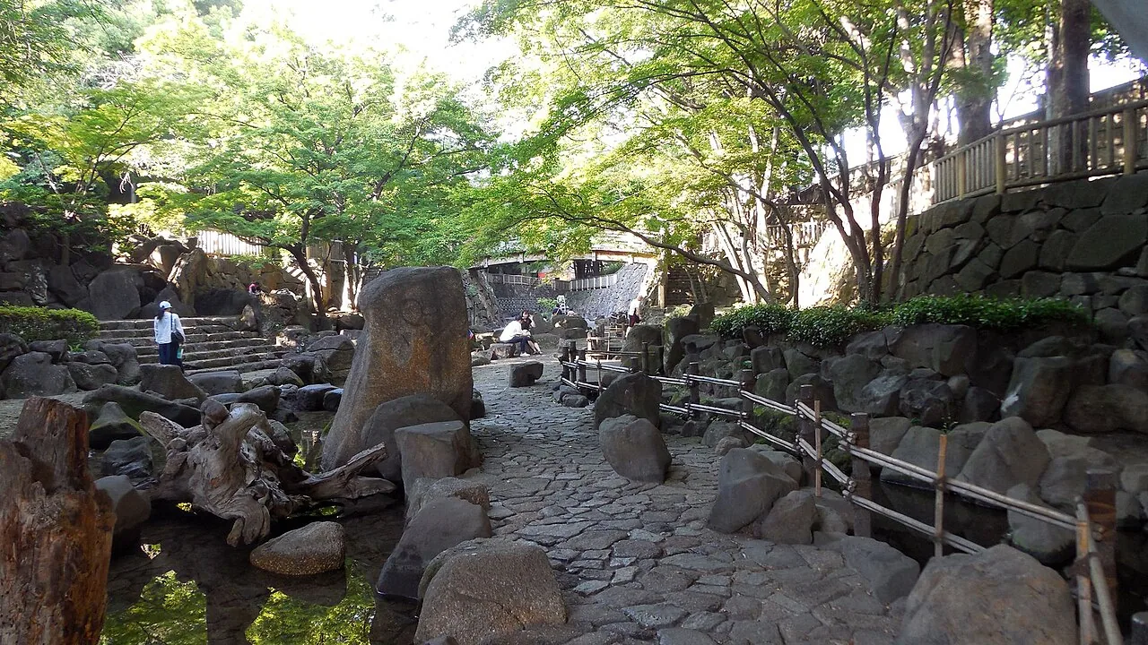 A wooden bridge and stone-lined stream in Otonashi Shinsui Park, Oji